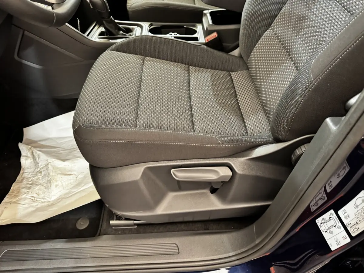 Vue rapprochée du siège avant droit gris foncé du Volkswagen Touran 2024, avec réglage manuel et porte ouverte bleu.
