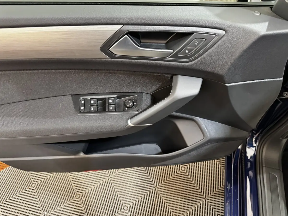 Vue intérieure côté conducteur de la porte avant bleu foncé du Volkswagen Touran 2024 avec commandes de vitres et verrouillage.