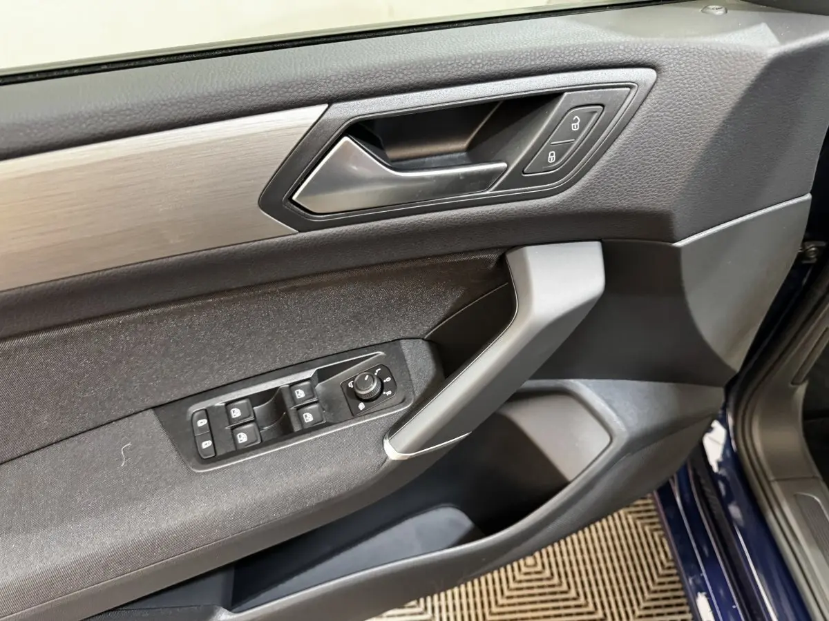 Vue intérieure côté conducteur de la porte d’un Volkswagen Touran bleu avec commandes de vitres et verrouillage.