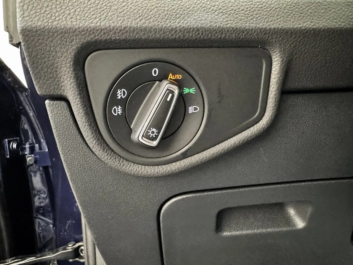 Gros plan sur le bouton de commande des phares dans l’habitacle du Volkswagen Touran bleu, côté conducteur.