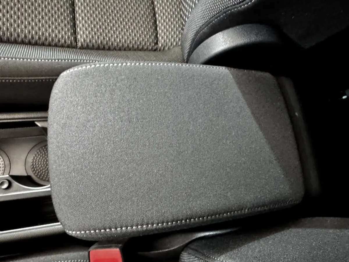 Détail de l'accoudoir central noir en tissu dans l'habitacle du Volkswagen Touran 2024, côté conducteur.