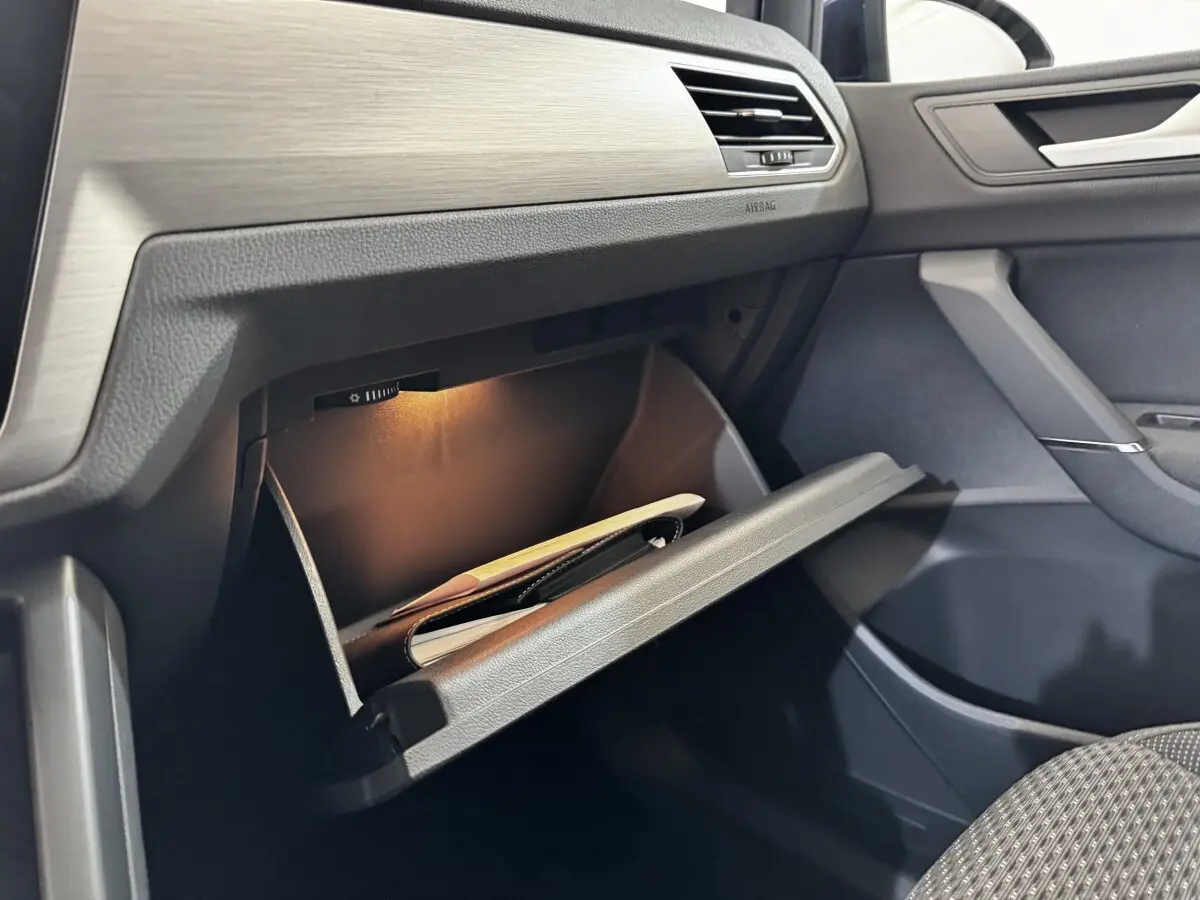 Vue intérieure côté passager du Volkswagen Touran 2024 avec boîte à gants ouverte et éclairage intérieur allumé.