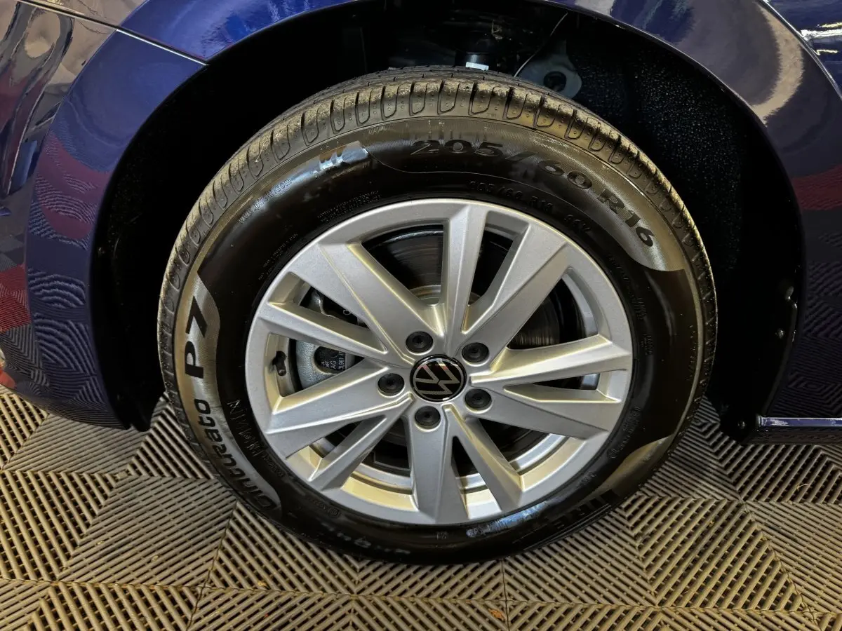 Gros plan sur la roue avant droite du Volkswagen Touran bleu 2024 avec jante alliage argentée et pneu Pirelli.