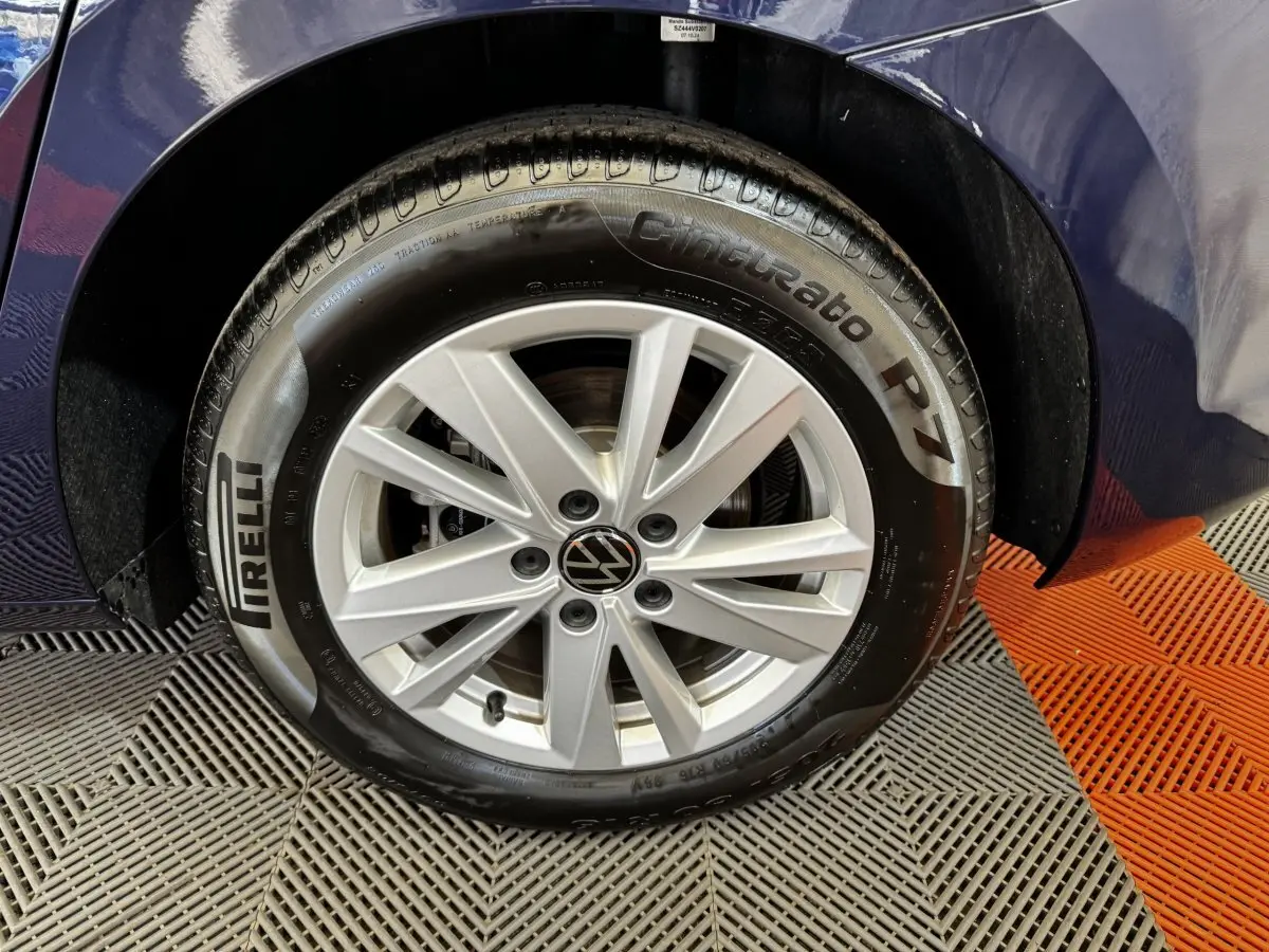 Gros plan sur la roue avant droite d’un Volkswagen Touran bleu 2024 avec jante argentée et pneu Pirelli Cinturato P7.