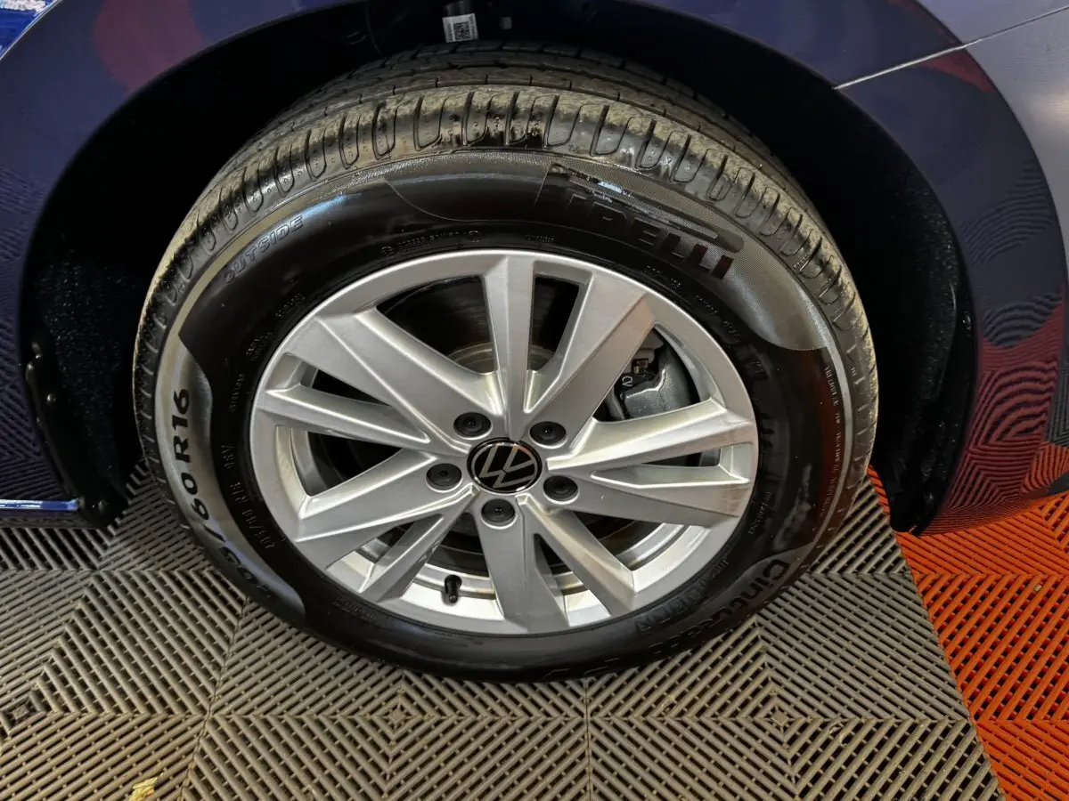 Gros plan sur la roue avant droite d’un Volkswagen Touran bleu 2024 avec jante alliage argentée et pneu Pirelli.