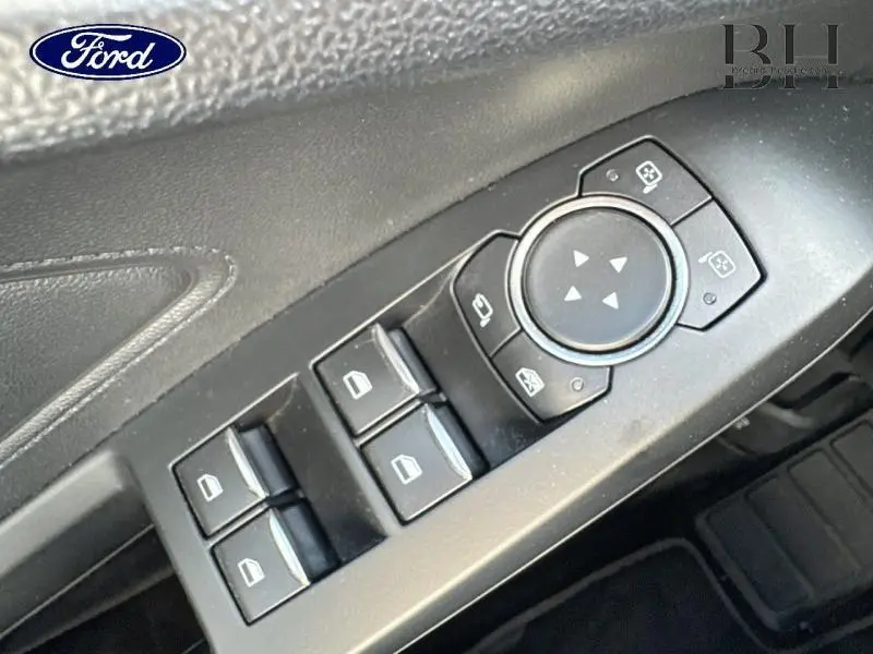 Gros plan sur les commandes de vitres et rétroviseurs côté conducteur d'une Ford Focus 2020 rouge Premium Candy.