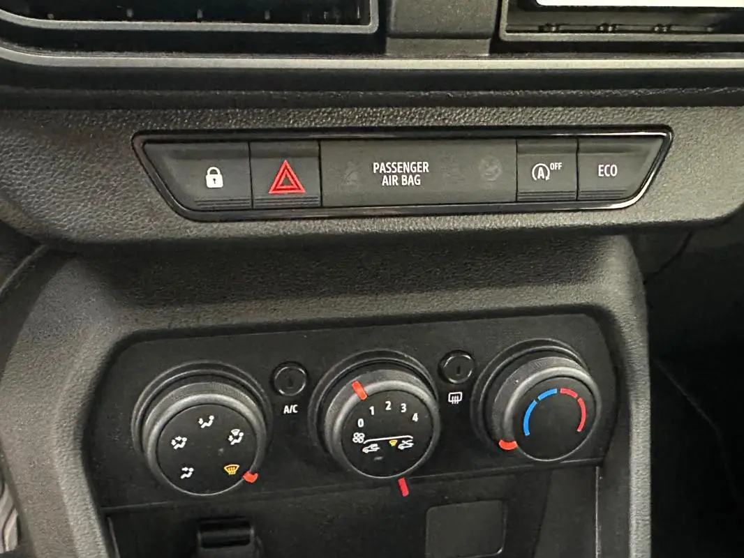 Gros plan sur la console centrale noire du Dacia Sandero 2024, montrant les commandes de climatisation manuelle.