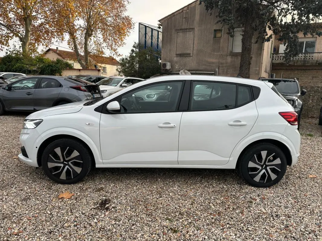 Vue de profil côté gauche d'une Dacia Sandero blanche 2024 avec jantes noires et détails modernes.