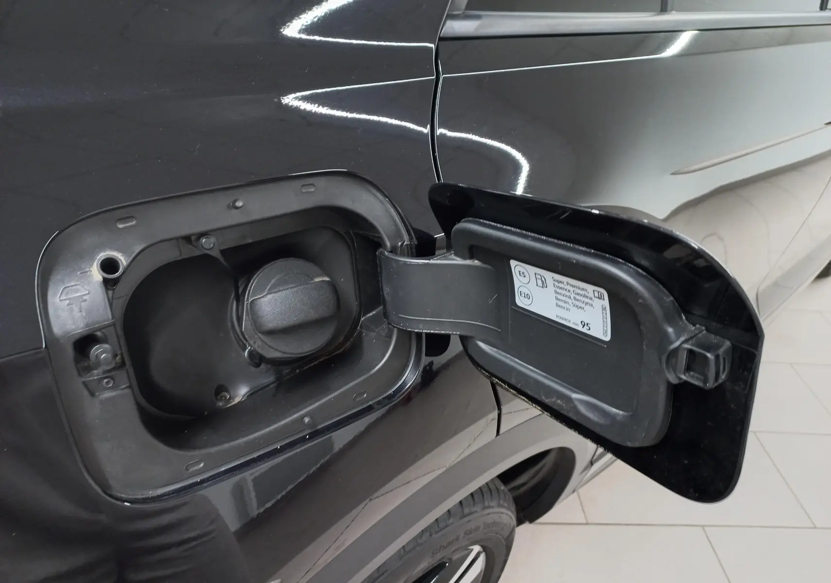 Vue rapprochée du bouchon de réservoir essence ouvert sur le côté gauche du Volkswagen T-Roc noir intense 2025.