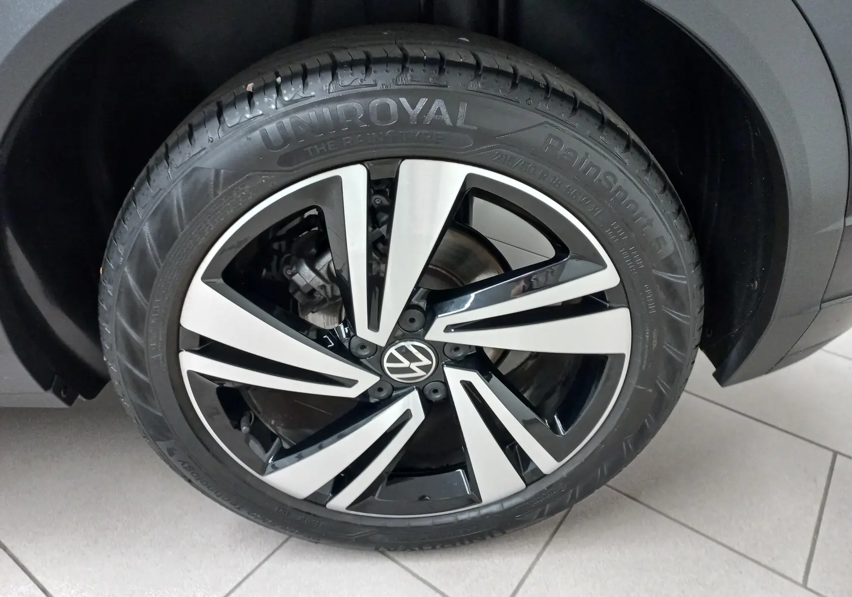 Gros plan sur la jante alliage bicolore noir et argent du Volkswagen T-Roc 1.5 TSI 150 DSG7 R-Line Noir Intense.