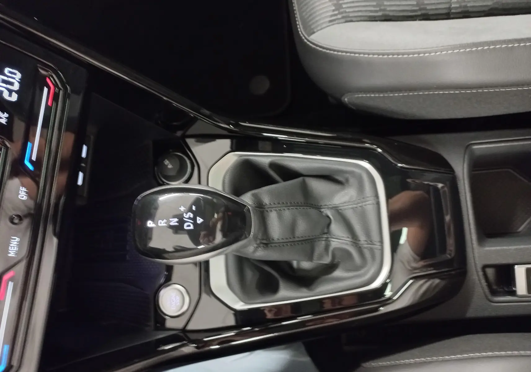Gros plan sur la console centrale du Volkswagen T-Roc 2025, levier de boîte auto DSG7 entouré de garniture noire brillante.