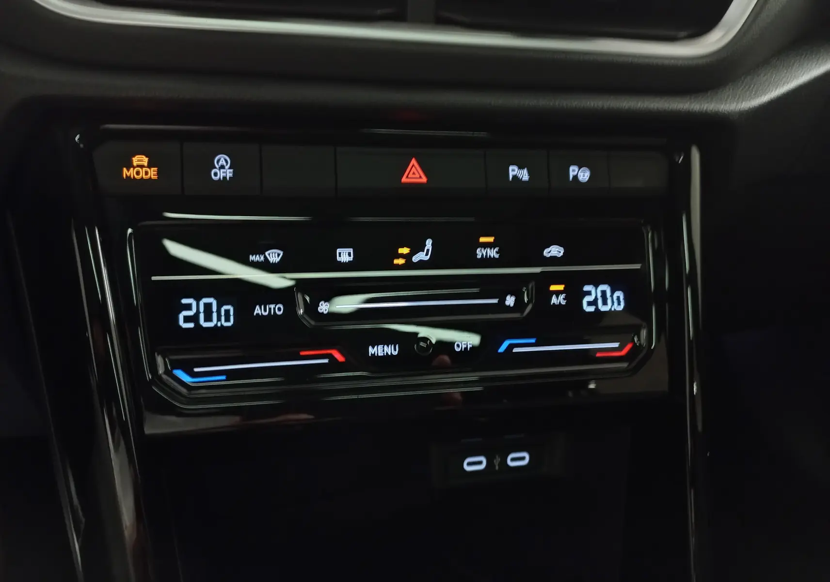 Vue rapprochée de la console centrale noire du Volkswagen T-Roc 2025 avec commandes climatisation digitale et boutons lumineux.