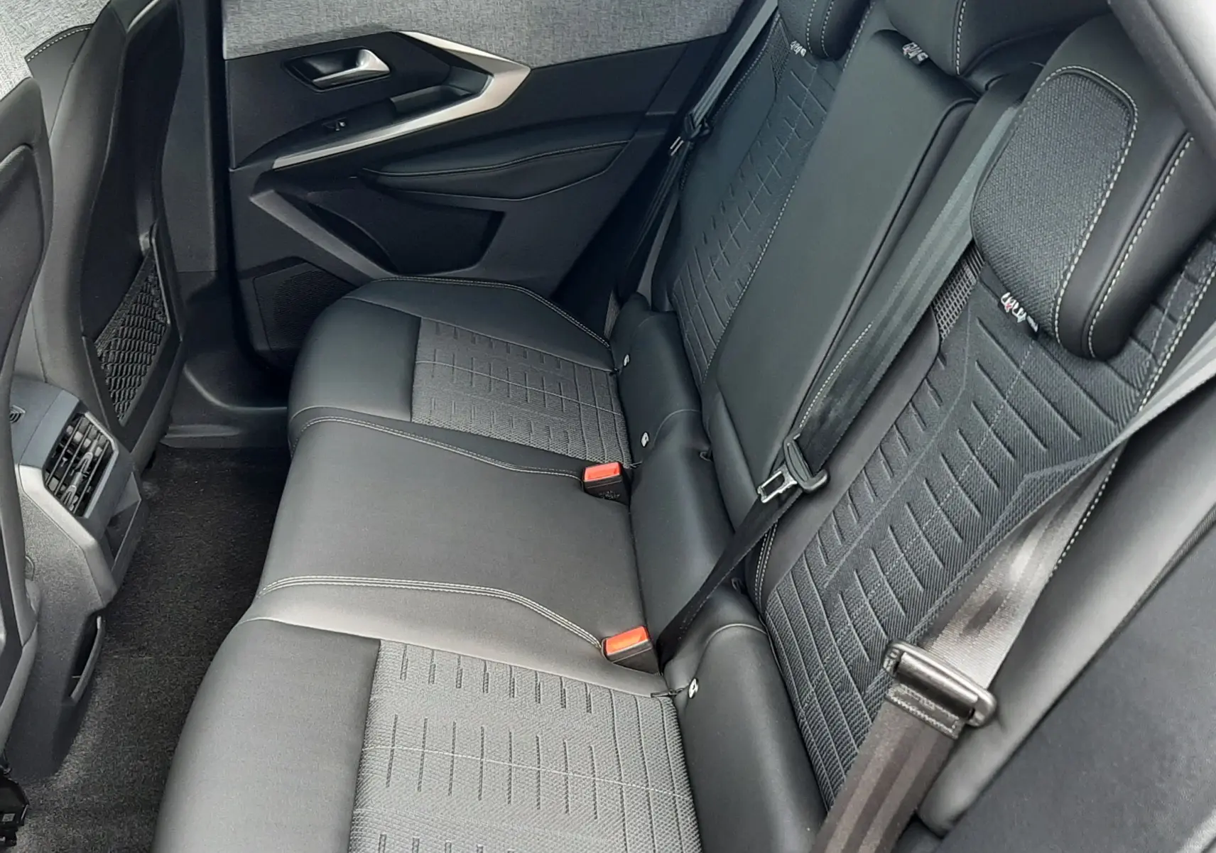 Vue intérieure côté droit des sièges arrière en tissu et cuir noir du Peugeot 3008 1.2 Hybrid 145ch GT, avec ceinture de sécurité.