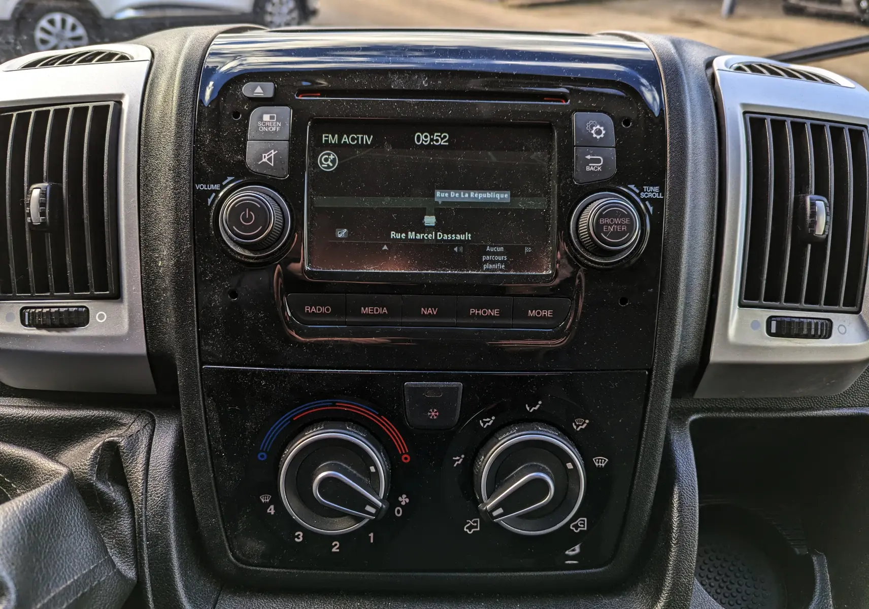 Vue rapprochée du tableau de bord noir du Fiat Ducato Fourgon 2019 avec écran tactile et commandes de climatisation.