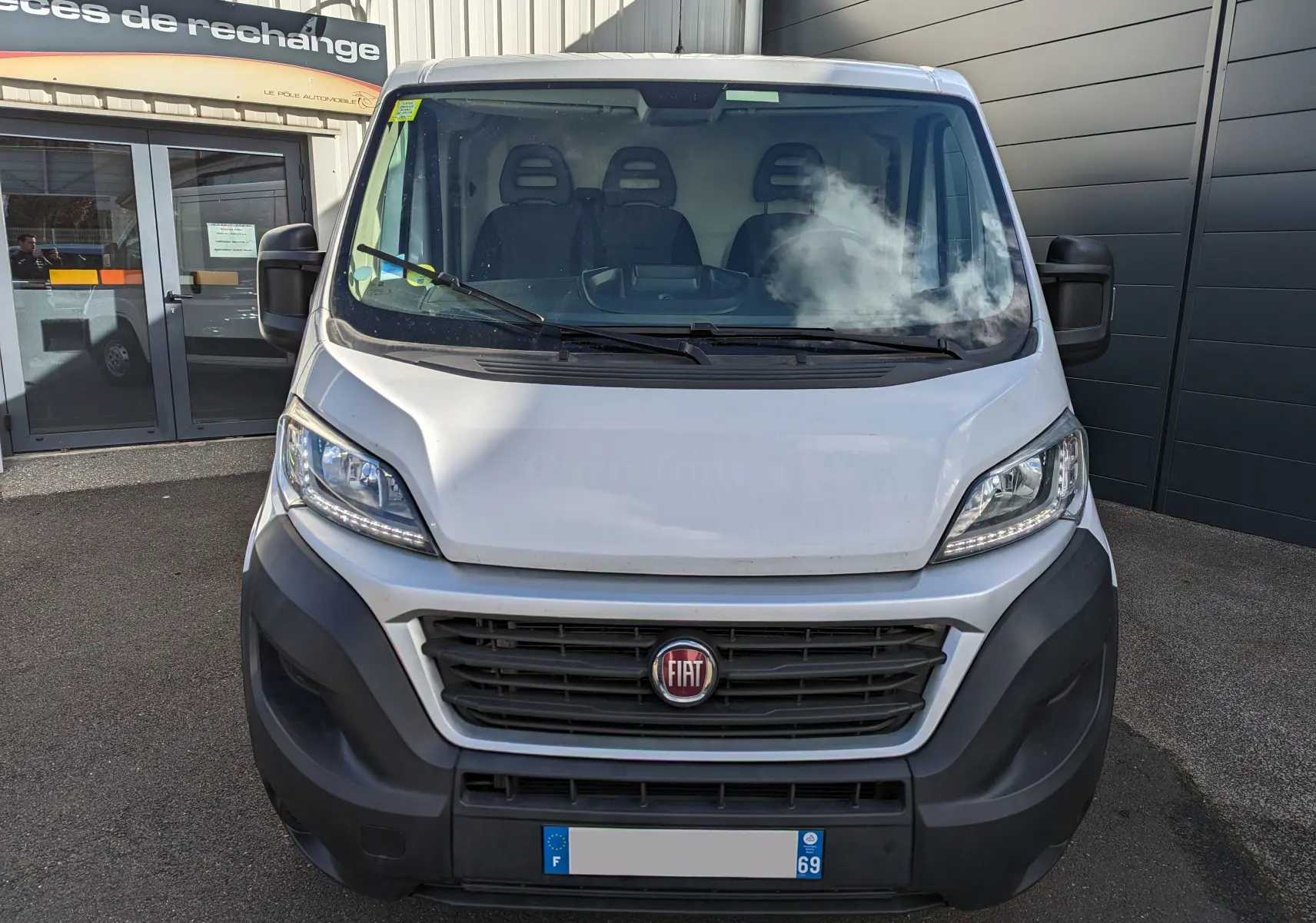 Vue frontale d'un FIAT Ducato Fourgon blanc 2019 avec calandre noire et trois sièges visibles à l'intérieur.