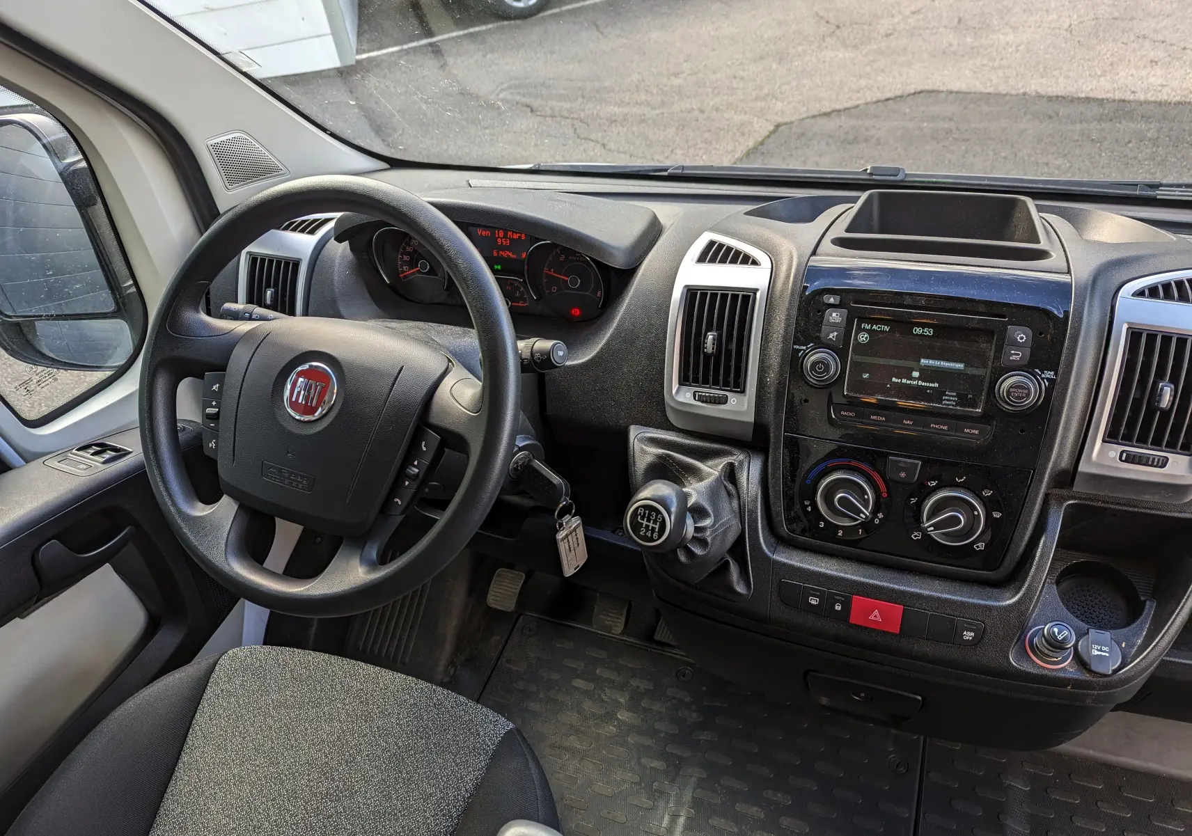 Vue intérieure du tableau de bord du Fiat Ducato Fourgon blanc 2019, volant à gauche et levier de vitesses manuel visible.