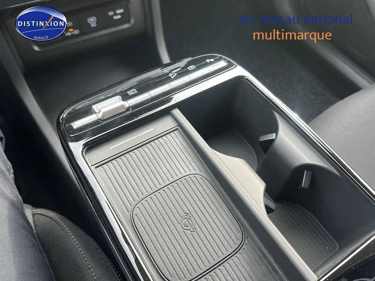 Gros plan sur la console centrale du Hyundai Tucson 2025 vert cyprès, mettant en valeur le chargeur sans fil et les porte-gobelets.