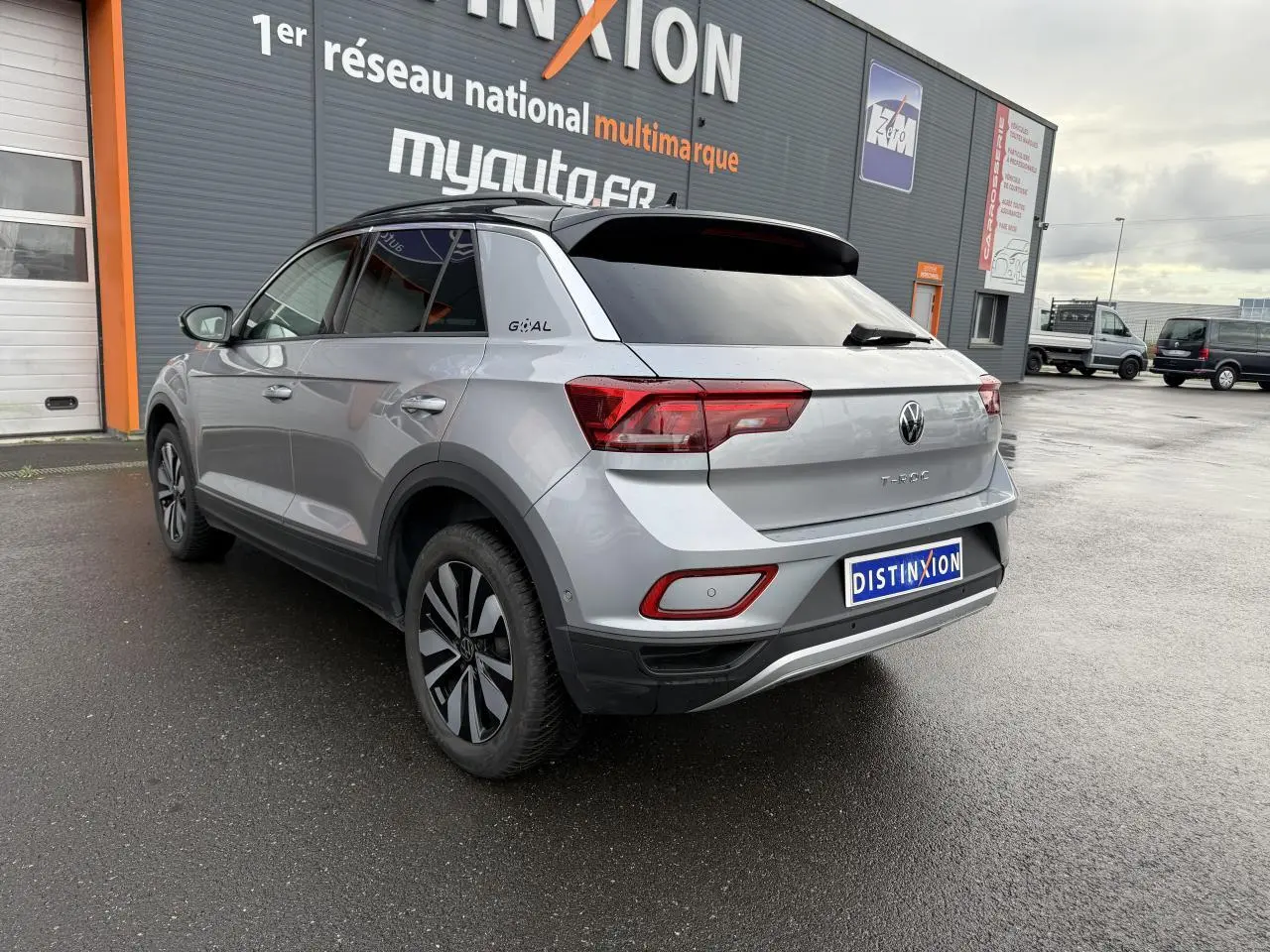 Vue 3/4 arrière droite d’un Volkswagen T-Roc argent pyrite métallisé avec jantes alliage et logo Goal sur le montant arrière.