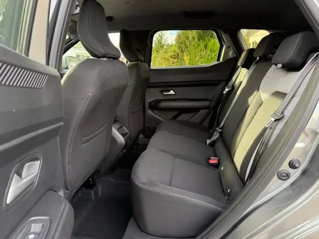 Vue intérieure arrière droite du Dacia Duster 1.8 Hybrid 155 Journey gris Schiste, mettant en valeur la sellerie spécifique et l'espace passagers.