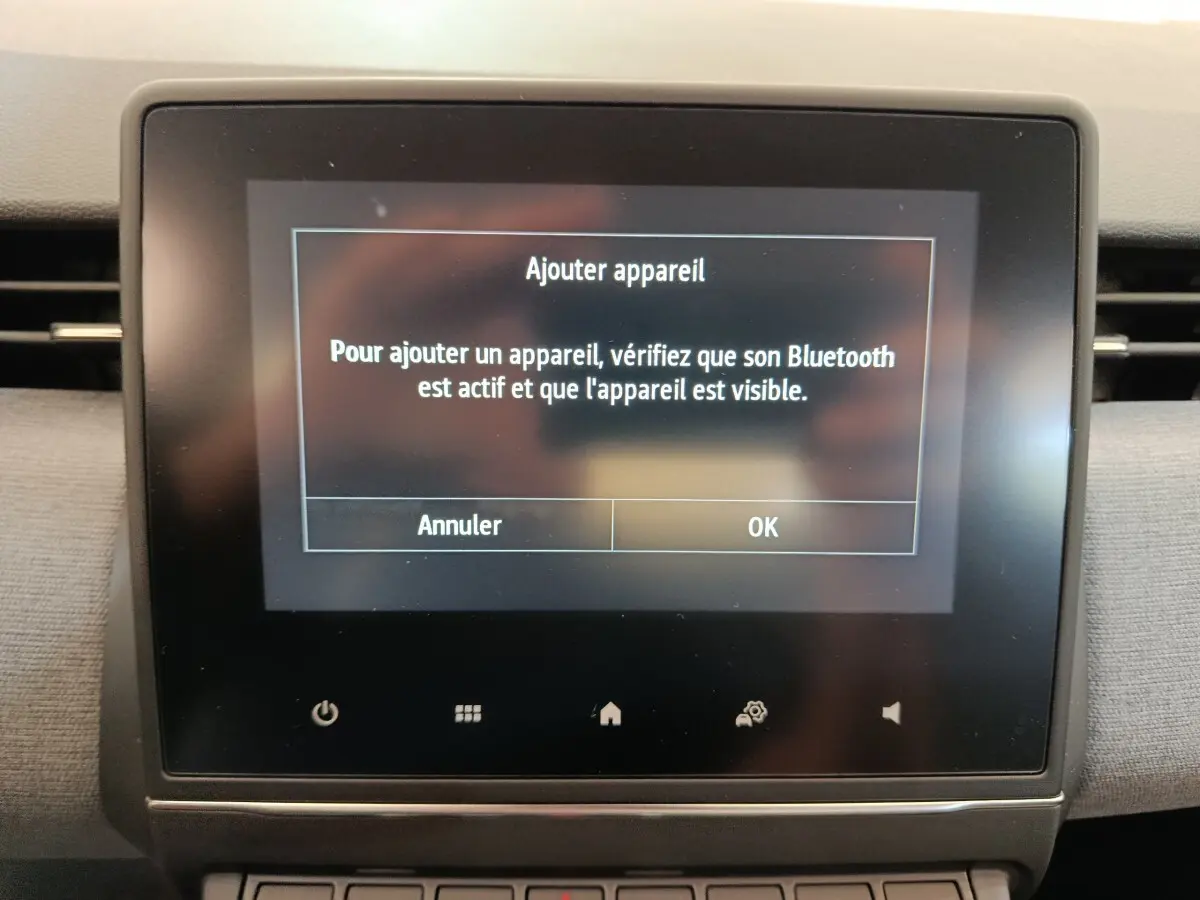 Écran tactile central de la Renault Clio blanche 2024 affichant un message d'ajout d'appareil Bluetooth.