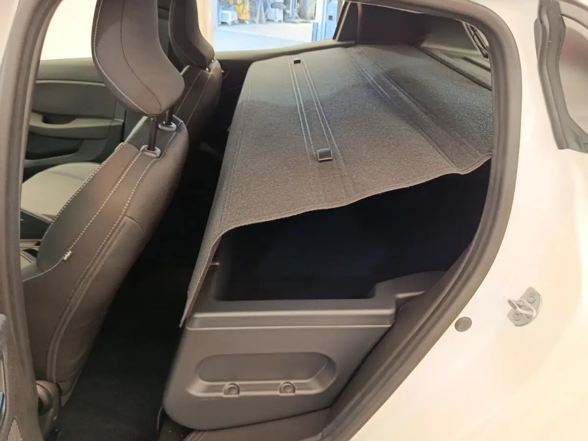 Vue intérieure côté droit de la Renault Clio blanche 2024 montrant la banquette arrière rabattue et le coffre sous la tablette.