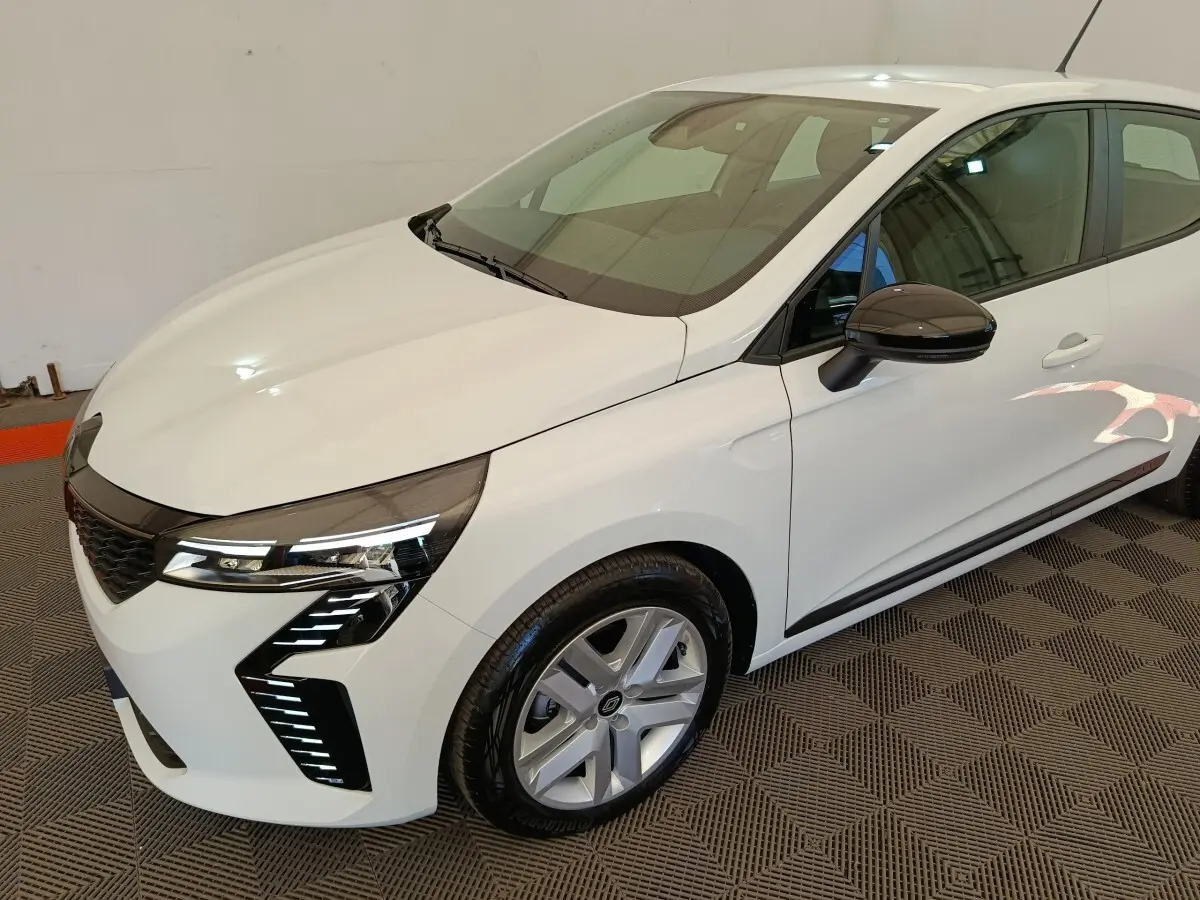 Renault Clio 2024 blanche vue 3/4 avant droit, avec phares LED distinctifs et rétroviseurs noirs.