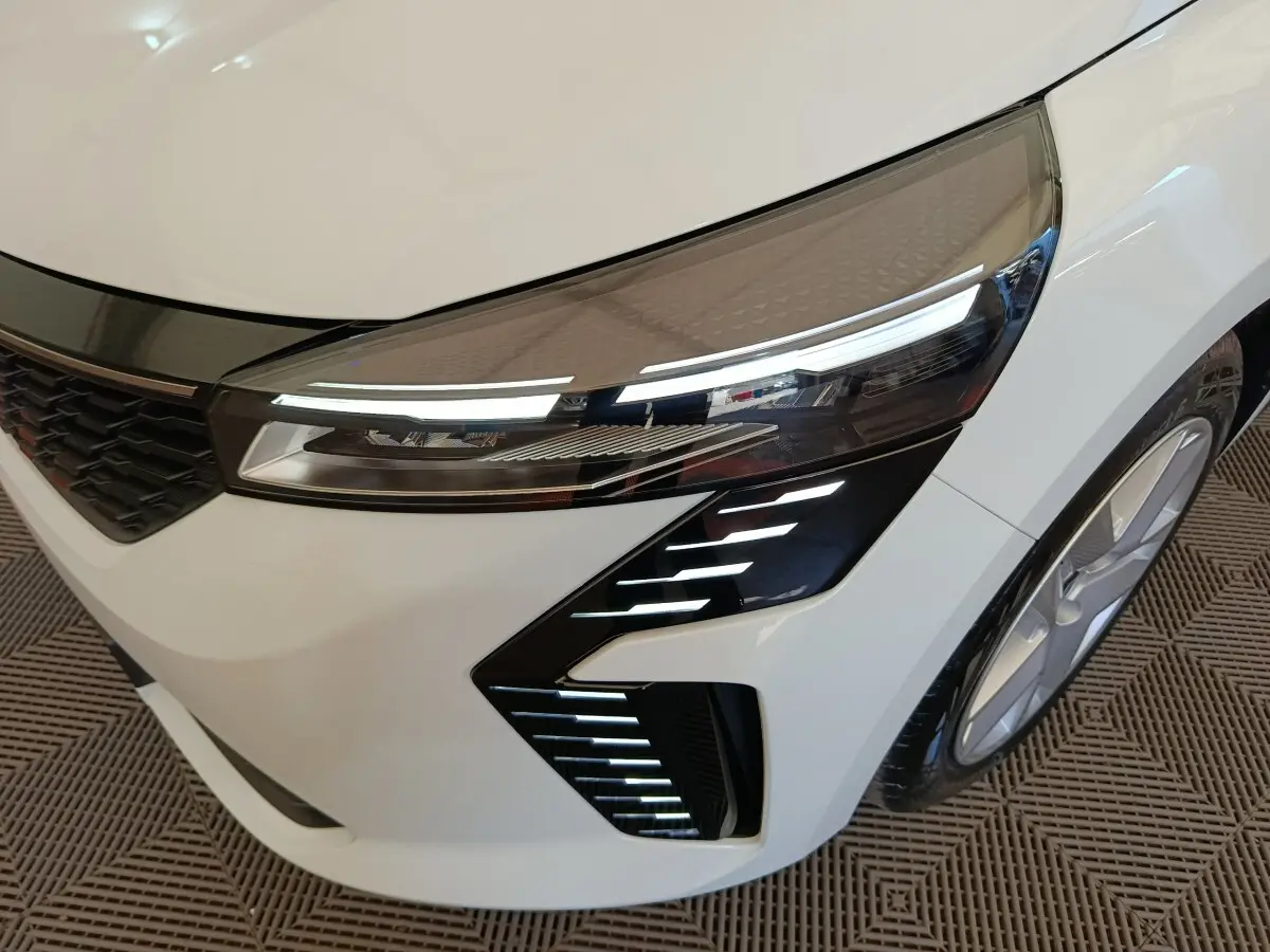 Gros plan sur l'avant droit blanc de la Renault Clio 2024, mettant en valeur les phares LED et la calandre noire.