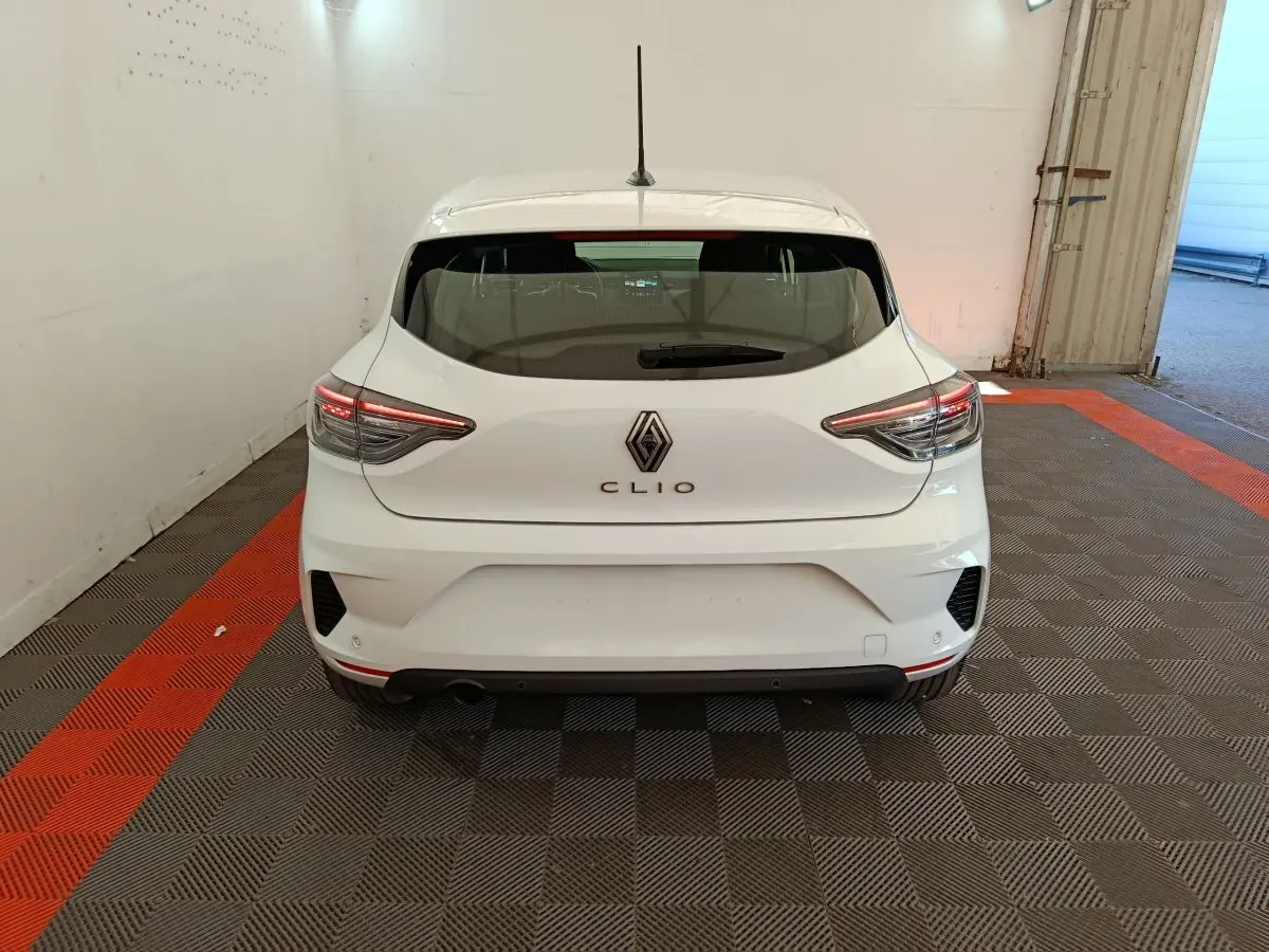Vue arrière d'une Renault Clio blanche 2024 avec feux LED et logo centré dans un garage.