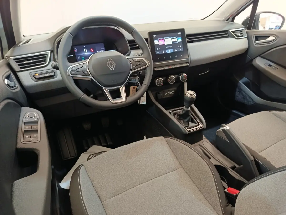 Vue intérieure avant droite de la Renault Clio 2024 avec tableau de bord numérique et volant multifonctions cuir synthétique.