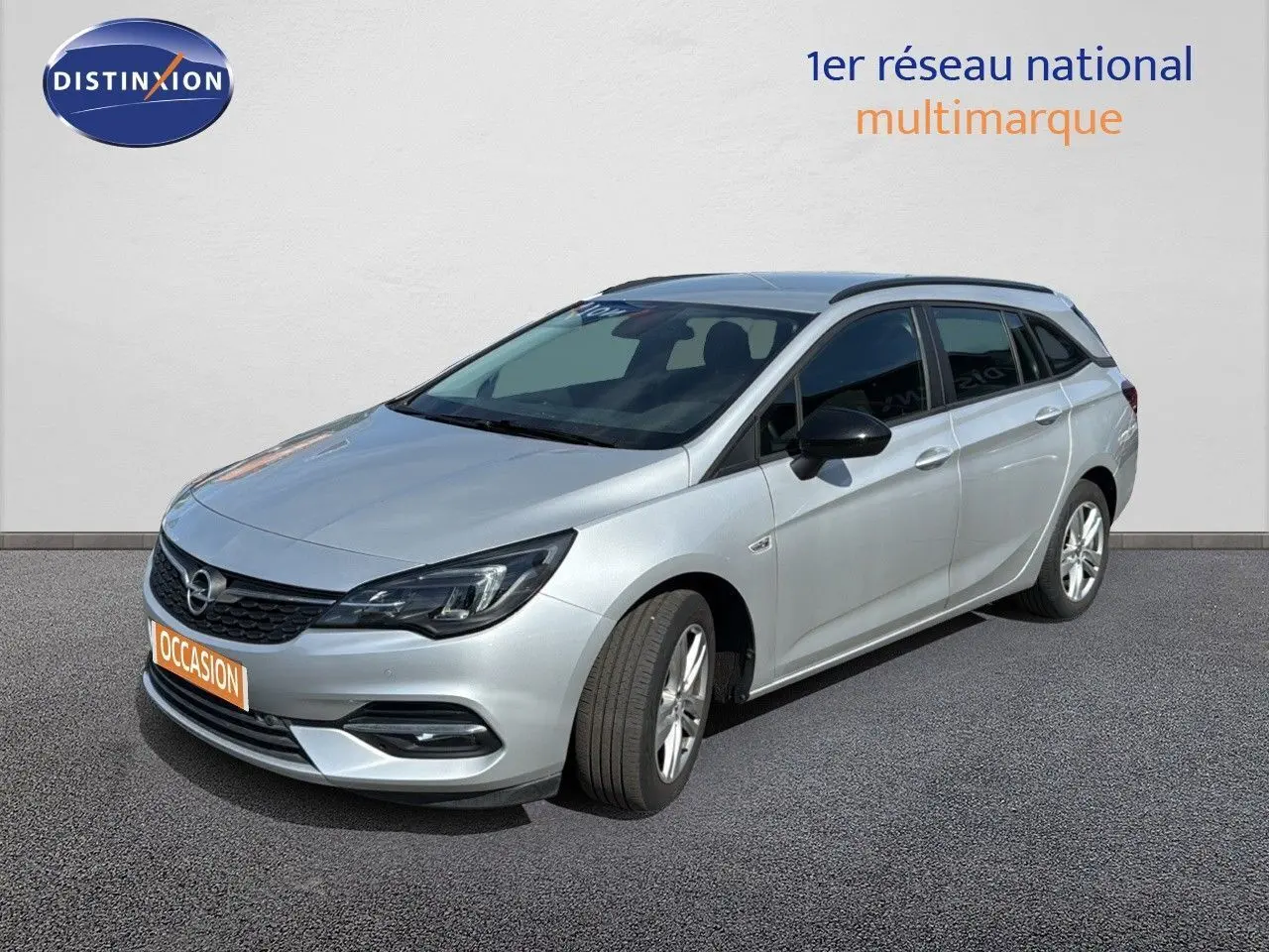 Opel Astra Sports Tourer gris minéral métal vue 3/4 avant droit sur fond neutre avec calandre noire.