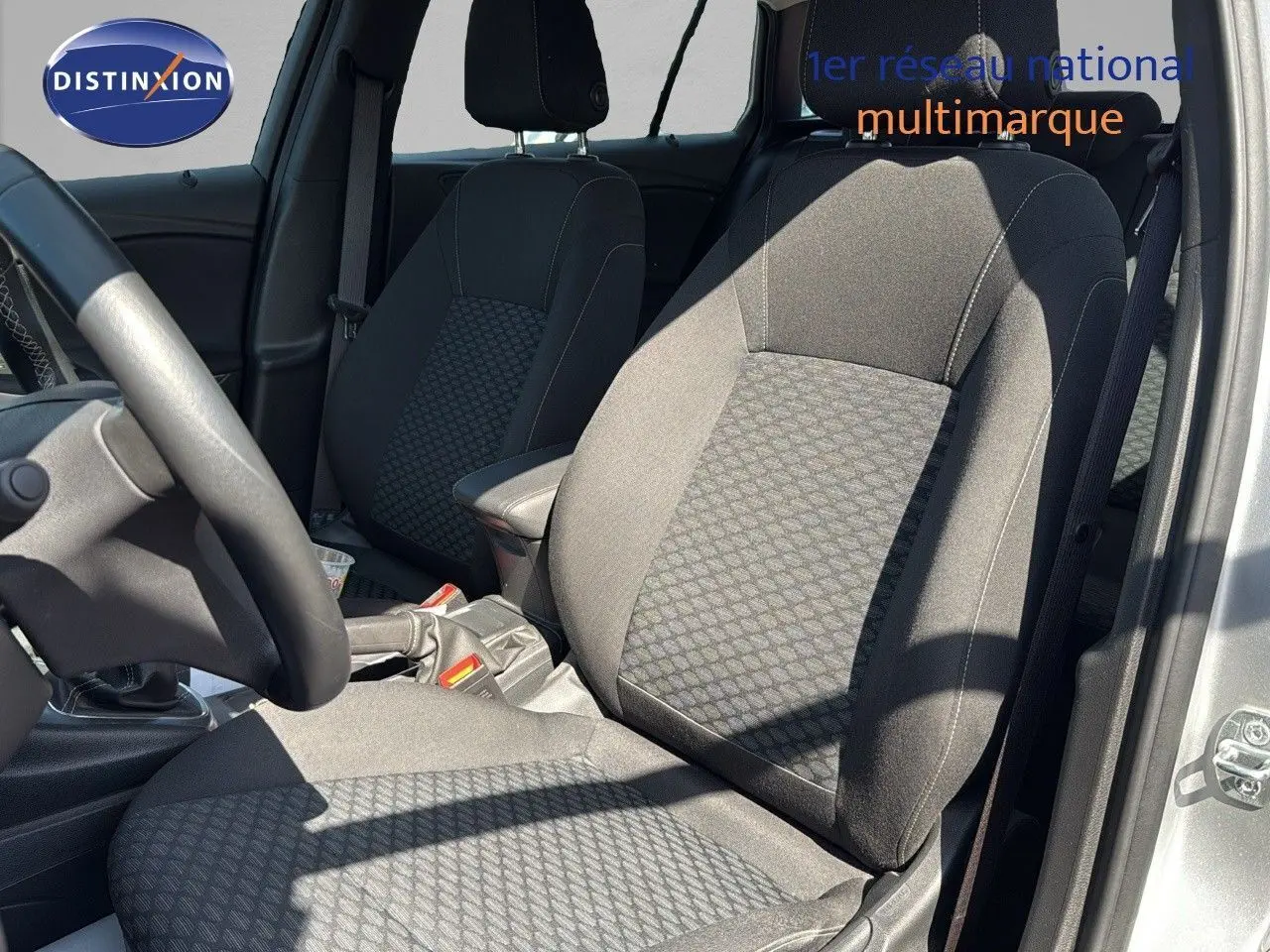 Vue intérieure côté conducteur de l'Opel Astra Sports Tourer gris minéral, mettant en valeur les sièges en tissu noir à motifs.