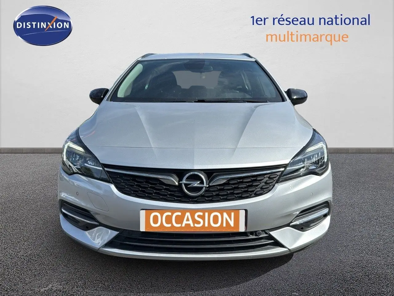 Vue frontale d'une Opel Astra Sports Tourer gris minéral métal avec calandre noire et phares LED allumés.