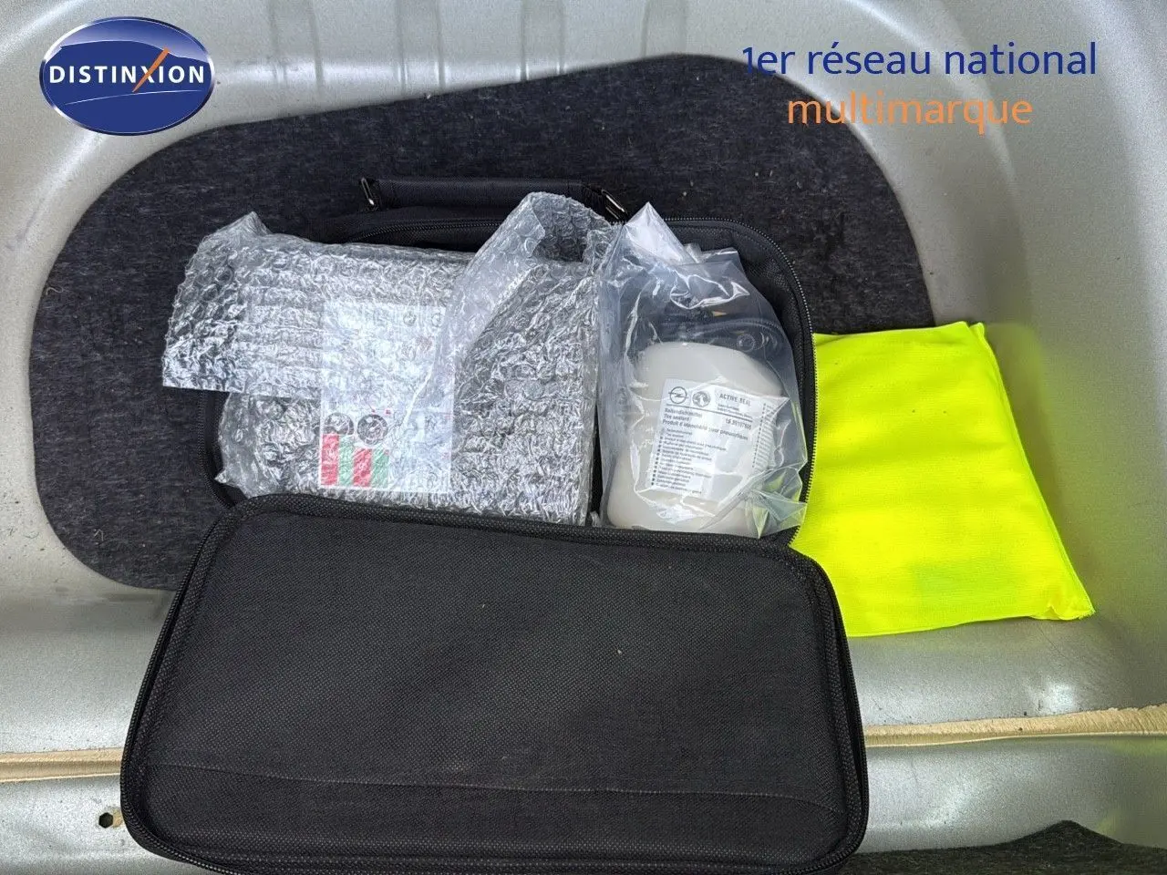 Coffre ouvert d'une Opel Astra Sports Tourer gris minéral, montrant un gilet jaune et une trousse de secours.