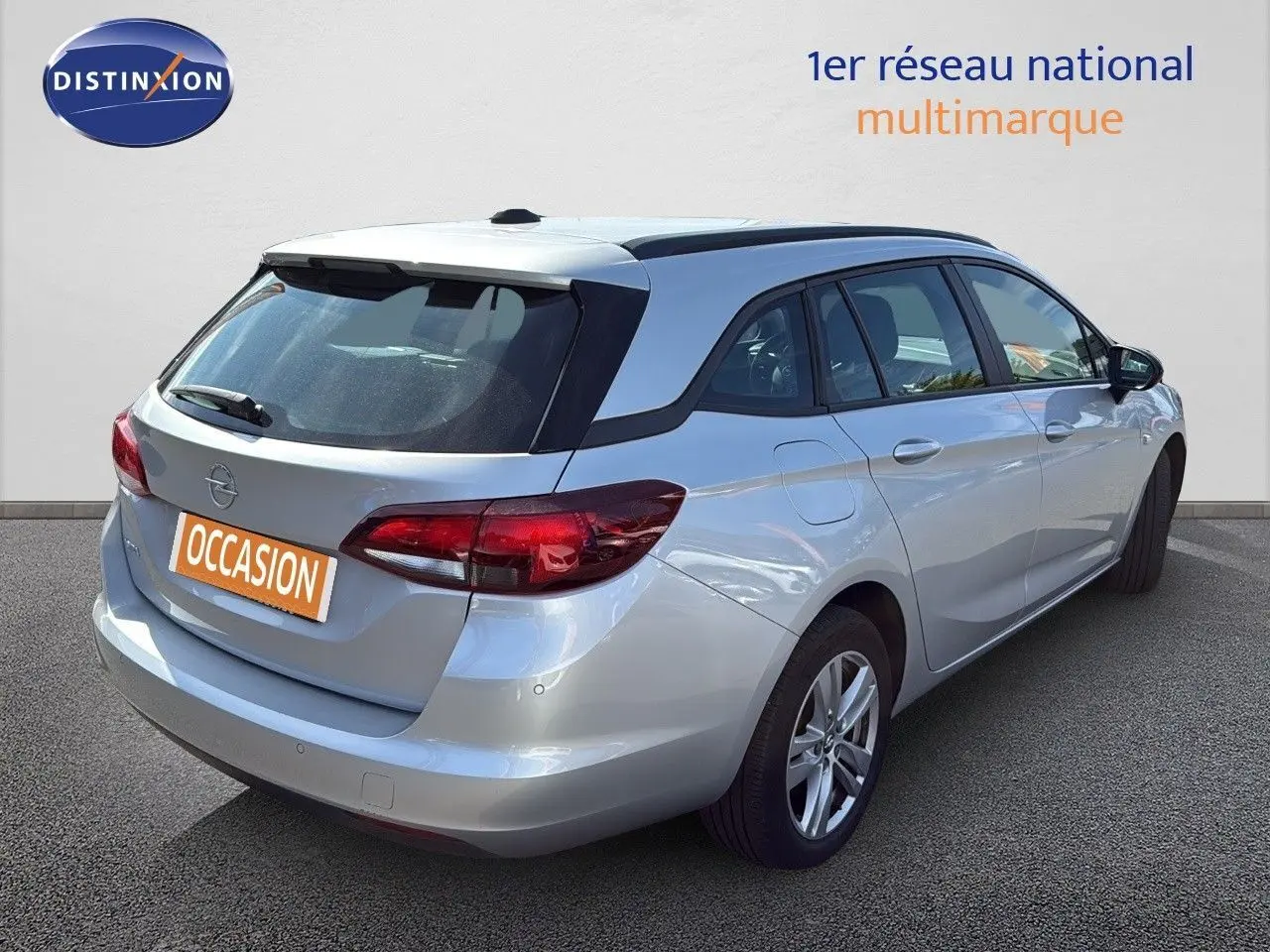 Vue 3/4 arrière droite d'une Opel Astra Sports Tourer gris minéral métal avec feux arrière LED et toit ouvrant.