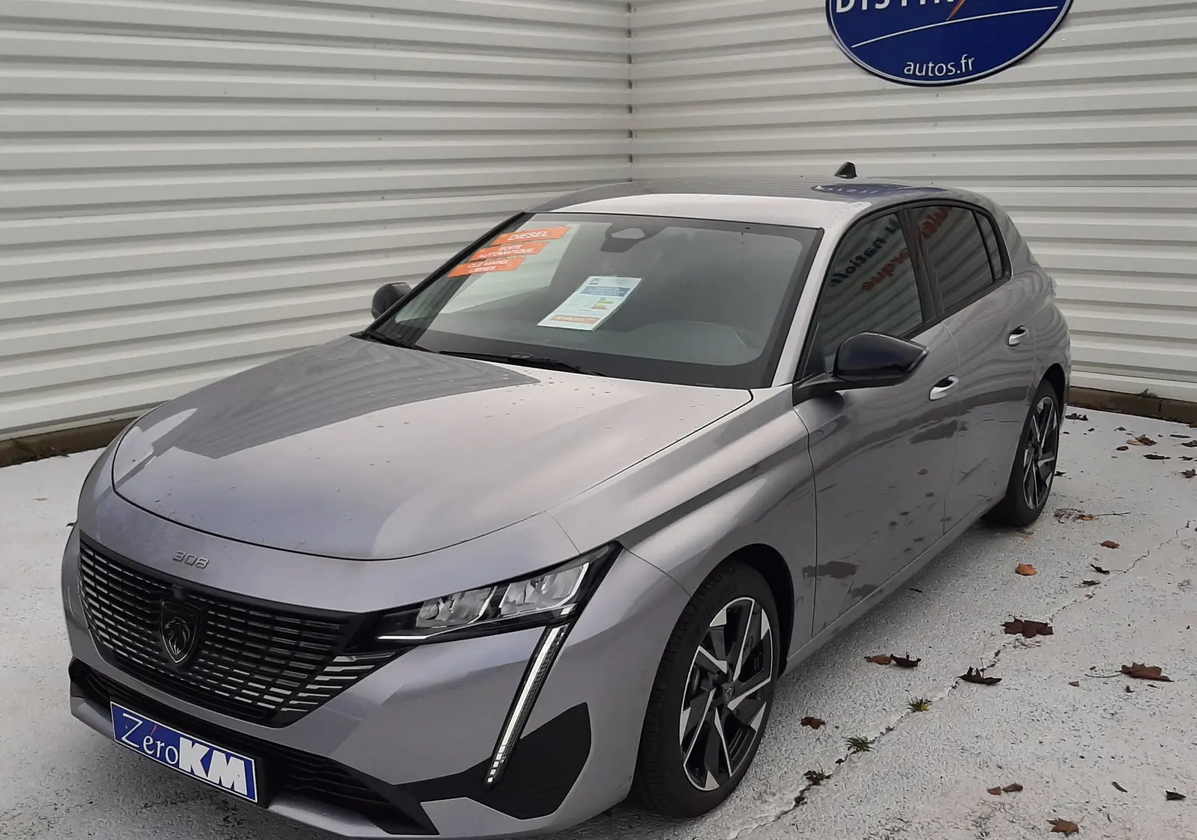 Peugeot 308 gris Artense vue 3/4 avant droit, avec calandre moderne et feux LED verticaux distinctifs.