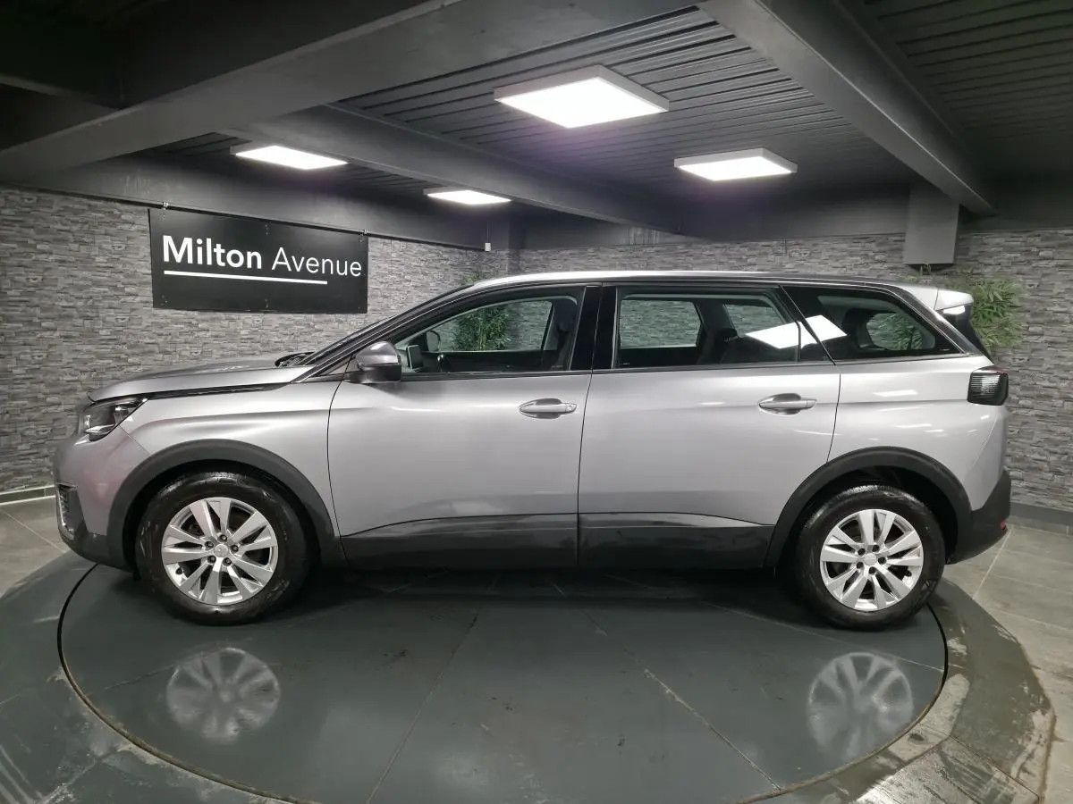 Profil côté gauche du Peugeot 5008 gris métallisé, SUV familial 7 places en intérieur showroom.