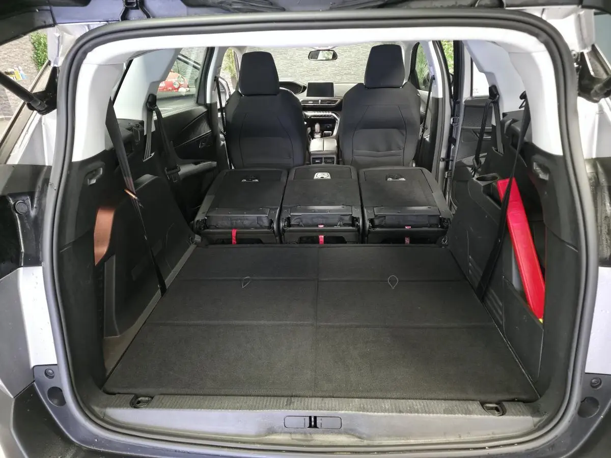 Vue arrière du coffre du Peugeot 5008 gris avec sièges arrière rabattus et intérieur spacieux visible jusqu'aux sièges avant.
