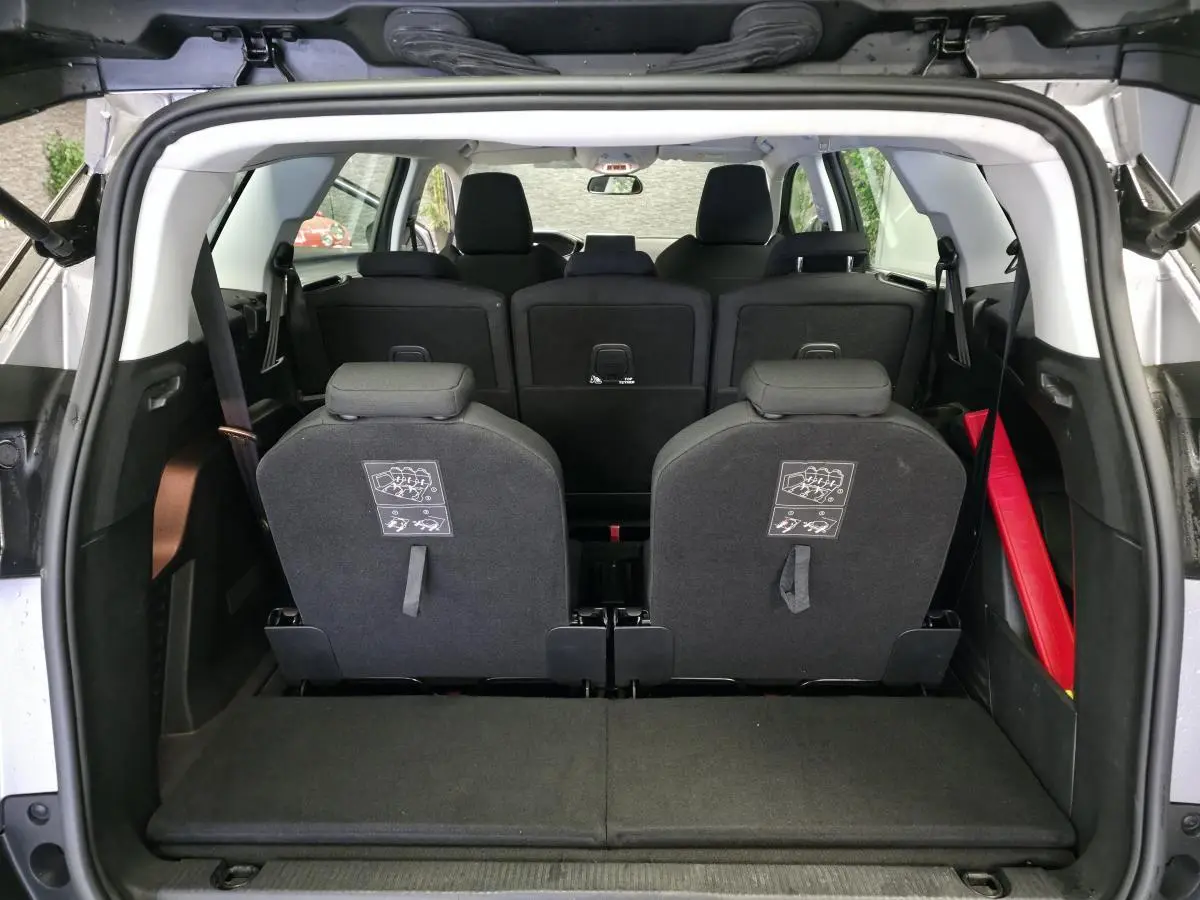 Vue arrière du coffre ouvert du Peugeot 5008 gris, montrant les sièges arrière escamotés et l'espace de chargement.