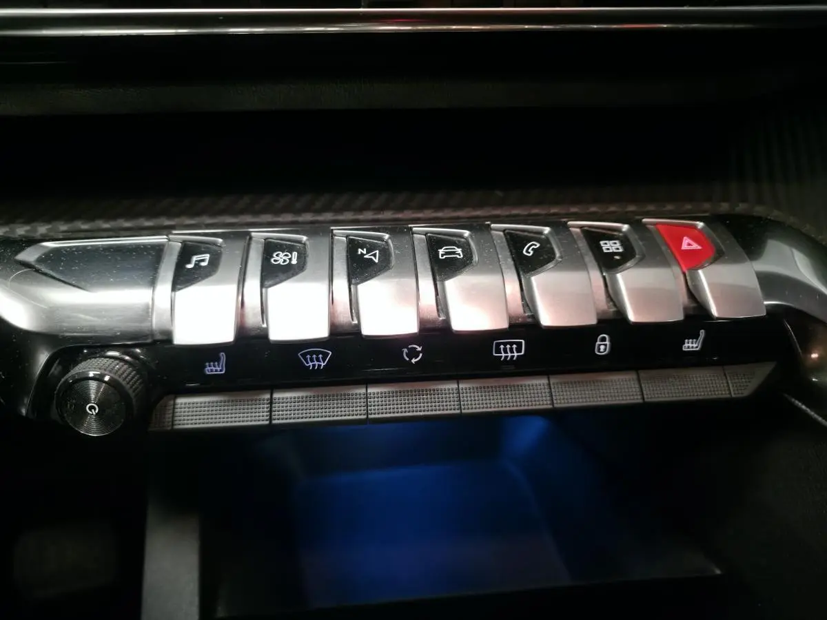 Gros plan sur la rangée de commandes chromées et boutons lumineux du tableau de bord du Peugeot 5008 gris 2020.