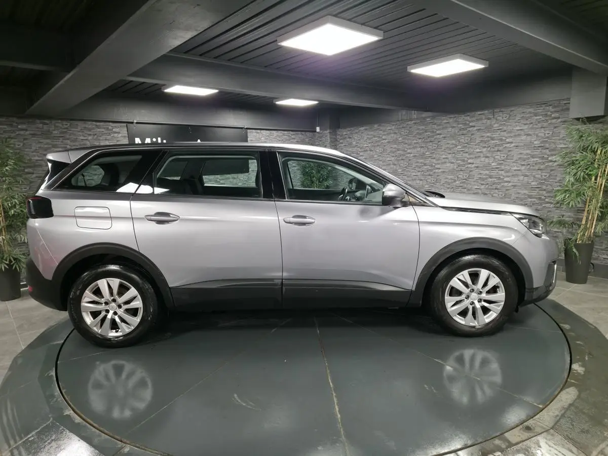 Peugeot 5008 gris métallisé vue de profil côté gauche dans un showroom avec jantes alliage 17 pouces.