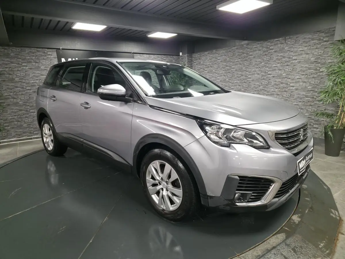 Peugeot 5008 gris métallisé vue 3/4 avant droit, avec calandre chromée et jantes alliage 17 pouces.
