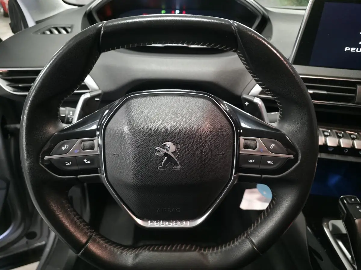 Volant en cuir noir de Peugeot 5008 2020 avec commandes intégrées, tableau de bord et écran tactile visibles en arrière-plan.