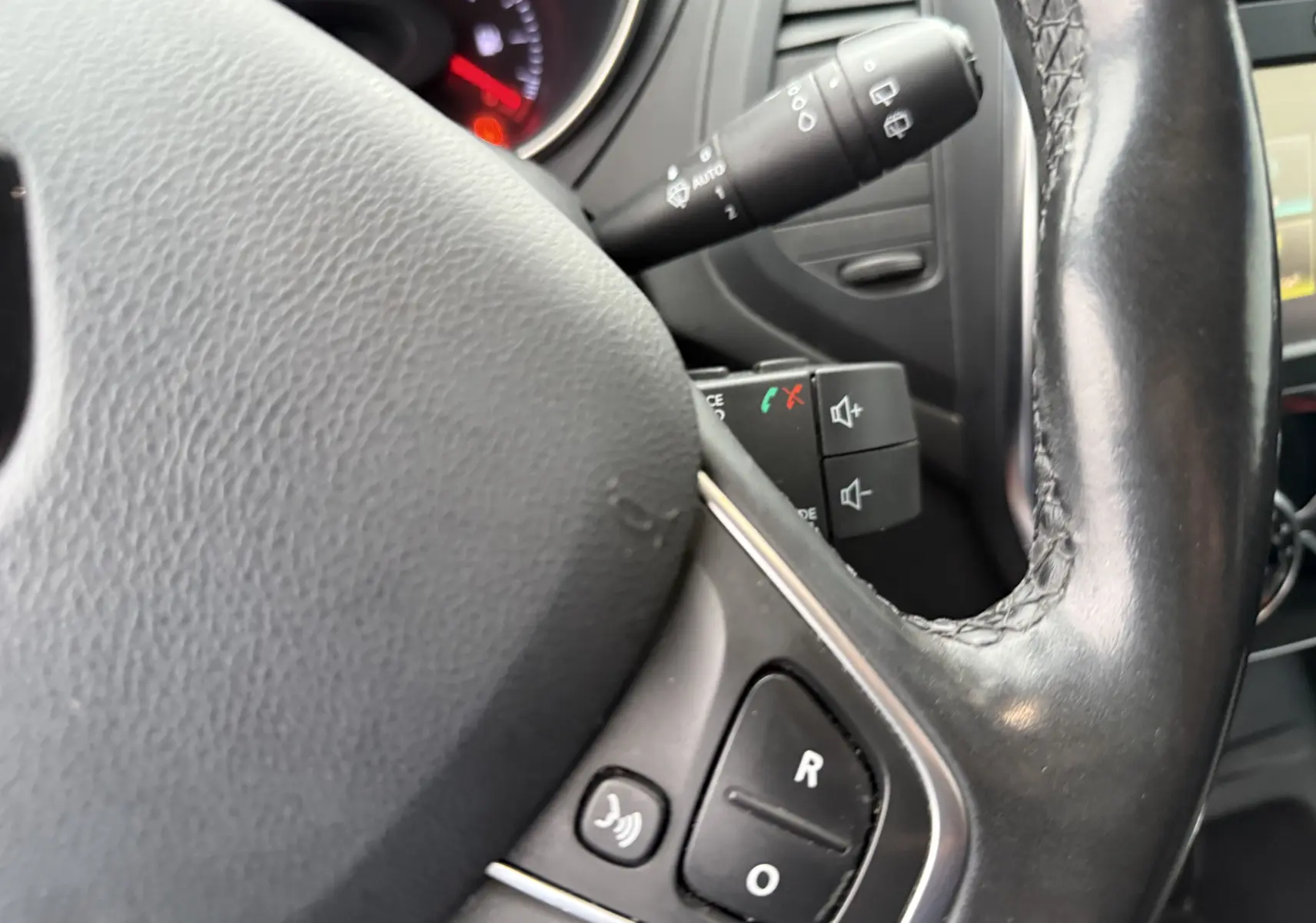 Gros plan sur le volant en cuir noir du Renault Captur TCE 120 EDC Intens, avec commandes audio intégrées.