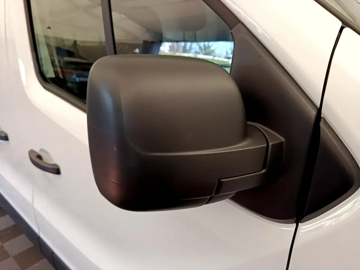 Gros plan sur le rétroviseur droit noir du Renault Trafic Fourgon blanc, vue latérale côté passager.