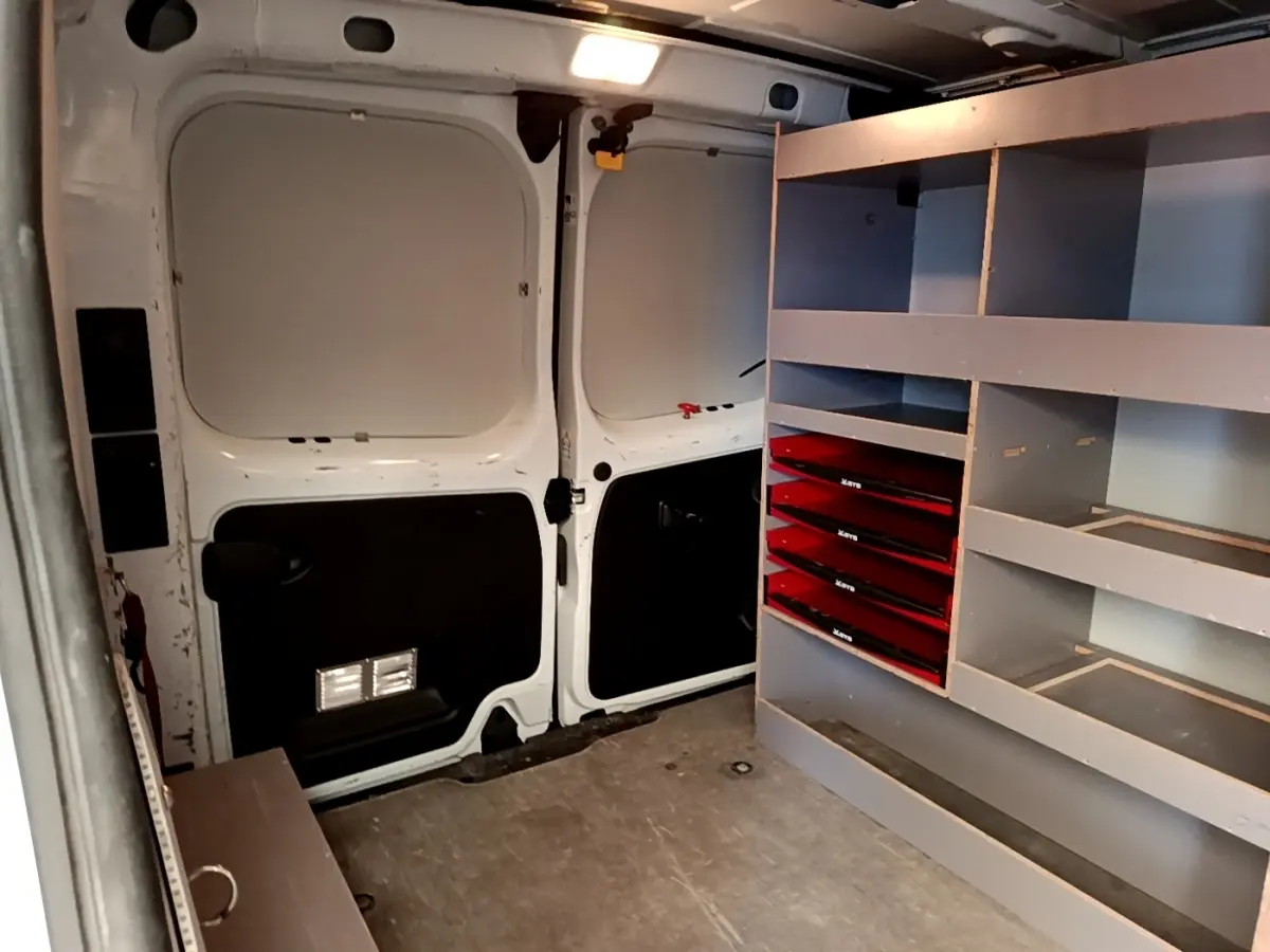 Vue intérieure arrière du Renault Trafic Fourgon blanc 2021, montrant l'aménagement avec étagères et tiroirs rouges.