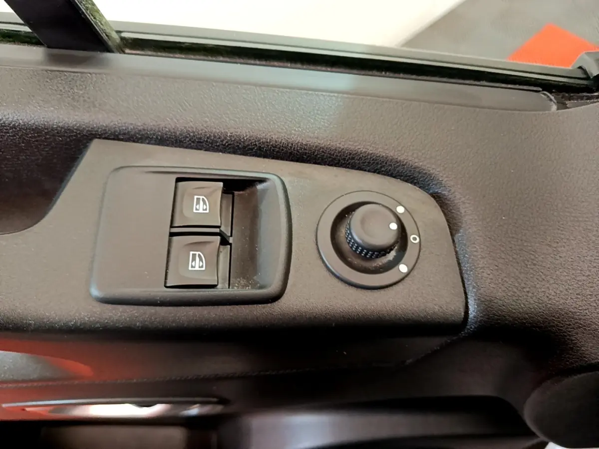 Gros plan sur les commandes de lève-vitres et réglage des rétroviseurs côté conducteur du Renault Trafic Fourgon blanc.