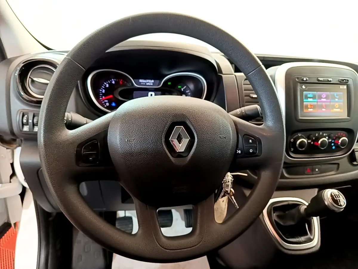 Vue intérieure centrée sur le volant noir Renault du Trafic Fourgon blanc avec tableau de bord et levier de vitesses manuel.