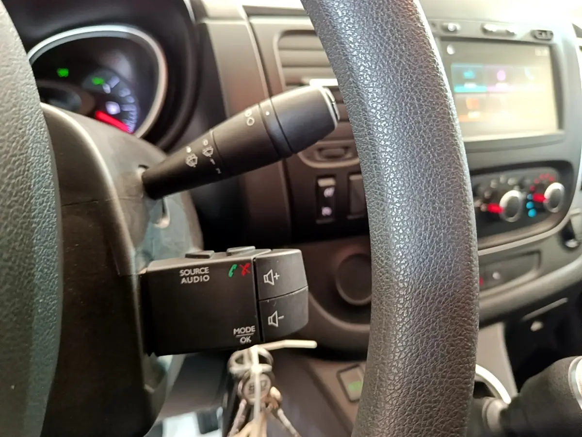 Détail du volant et commandes audio sur le tableau de bord intérieur du Renault Trafic Fourgon blanc, version 2021.