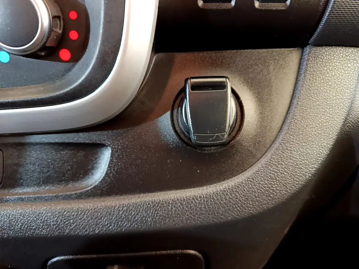 Gros plan sur la commande d’ouverture de la trappe à carburant du Renault Trafic Fourgon blanc, intérieur noir.
