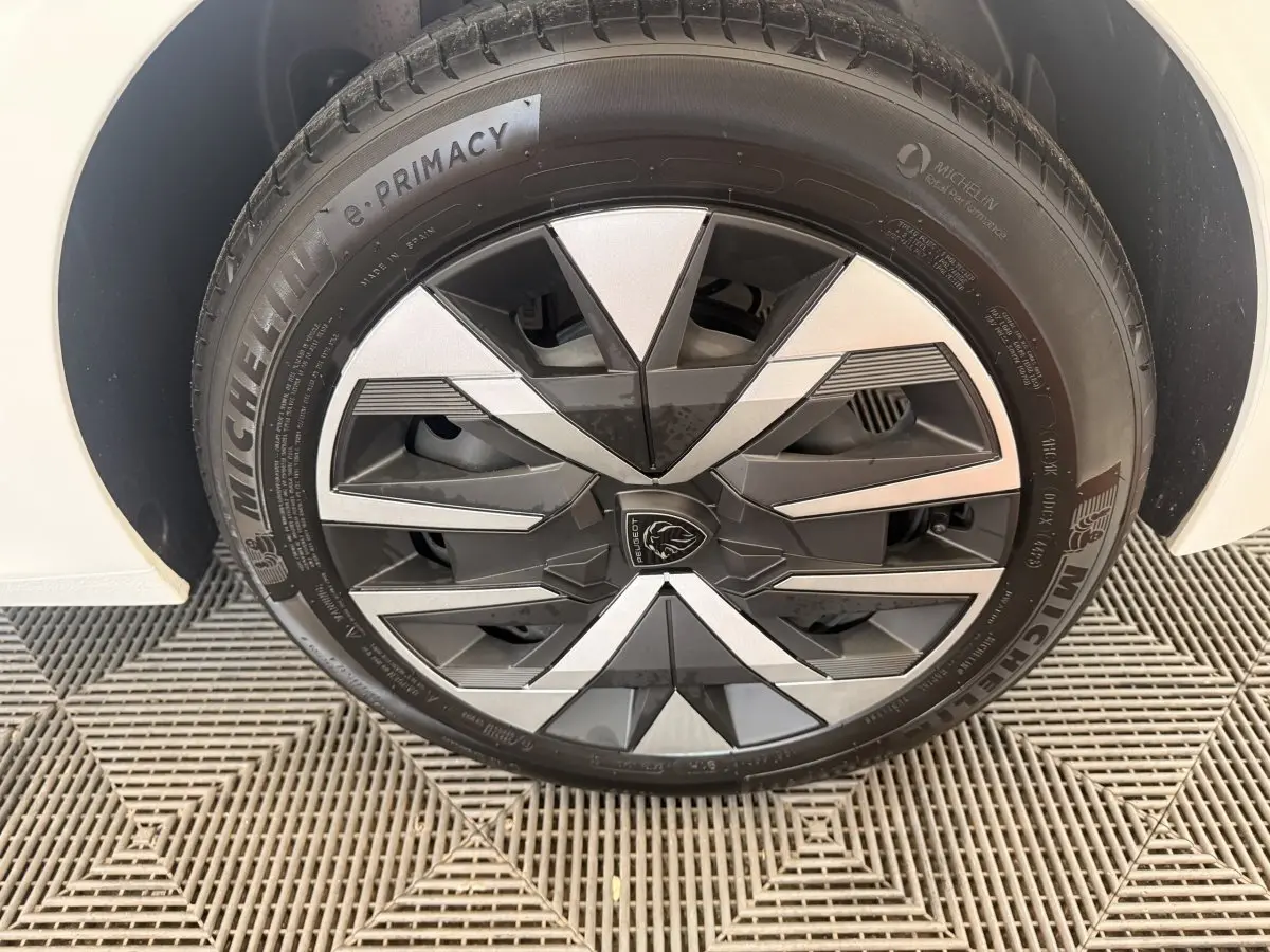 Gros plan sur la roue avant gauche blanche d’une Peugeot 208 2025 avec jante stylisée bicolore et pneu Michelin.